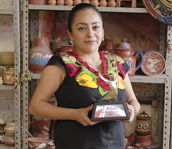Teresa Medina ganadora del Premio Emprendedores 2024, luciendo su trofeo frente a un fondo azul.