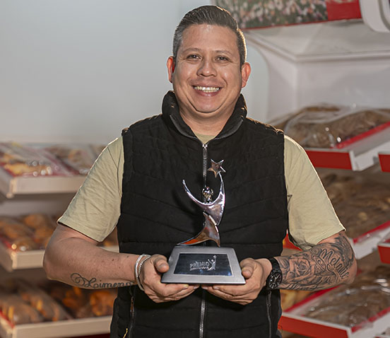 Magali Pedro en 2024, con trofeo en mano y blusa tradicional en una tienda de cerámica.